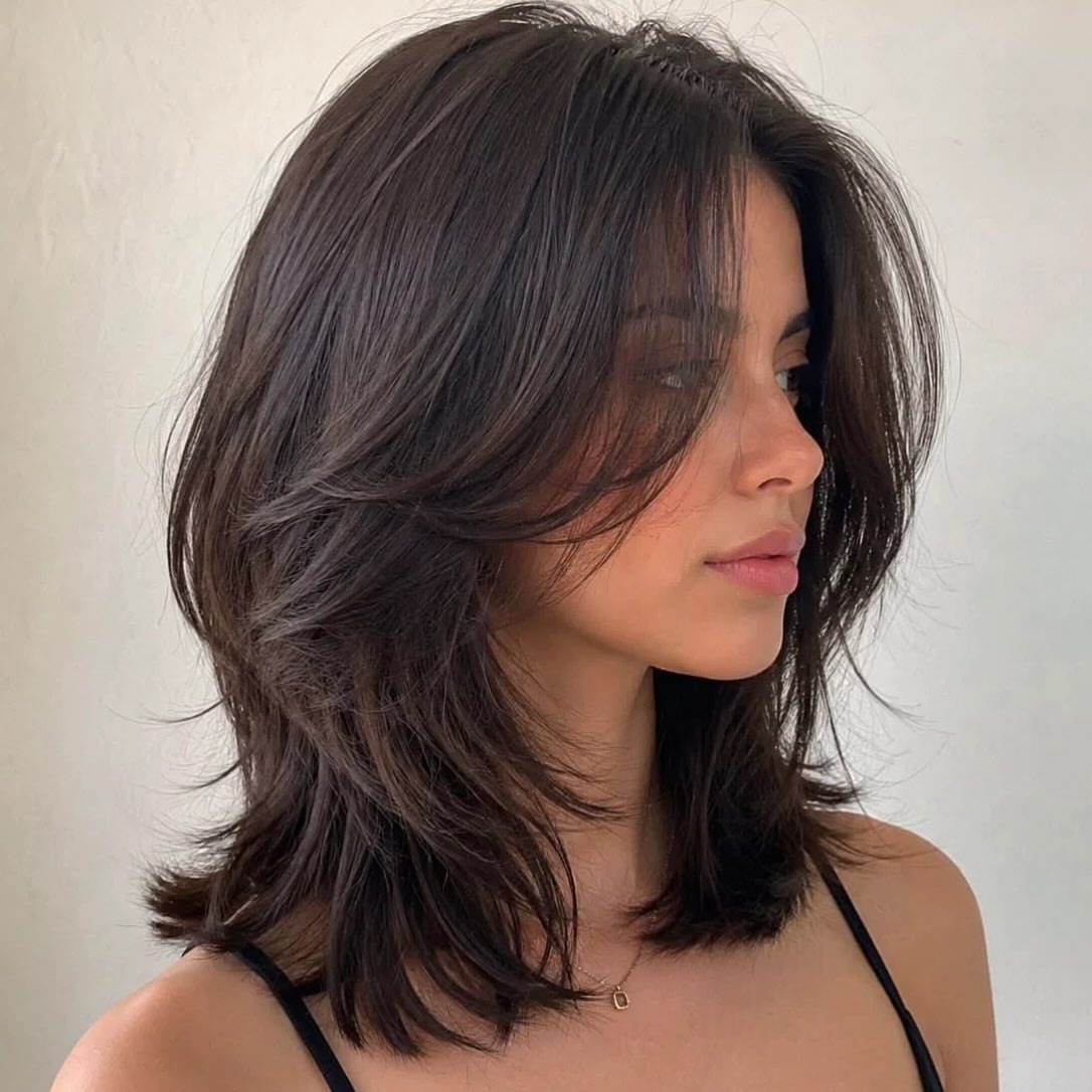 Woman with dark feathered lob and soft tapered layers framing her face