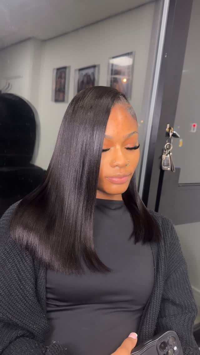 Woman with sleek, shoulder-length dark hair and a deep side part
