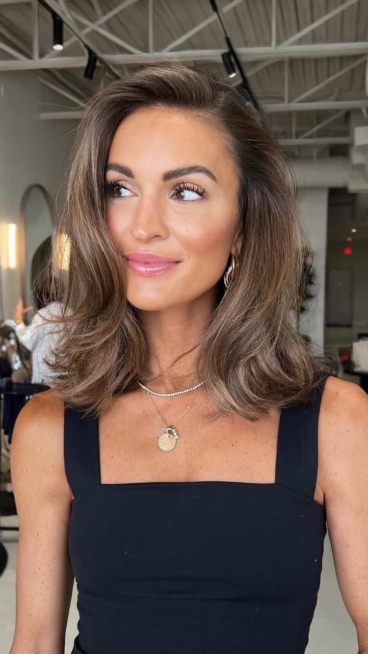 Woman with a voluminous, side-parted brown long bob and softly curled ends