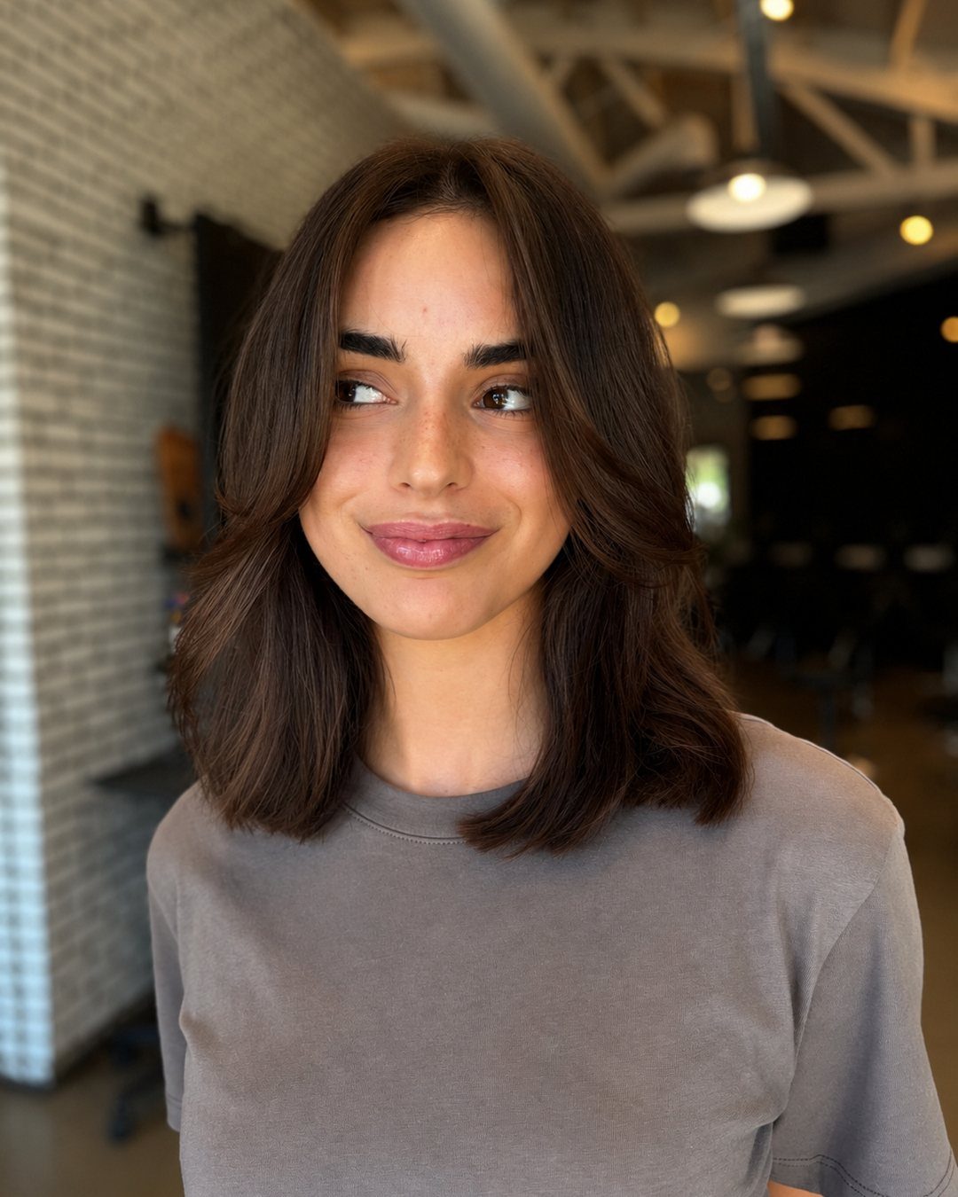 Woman wearing a dark brown long bob with soft waves and a center part