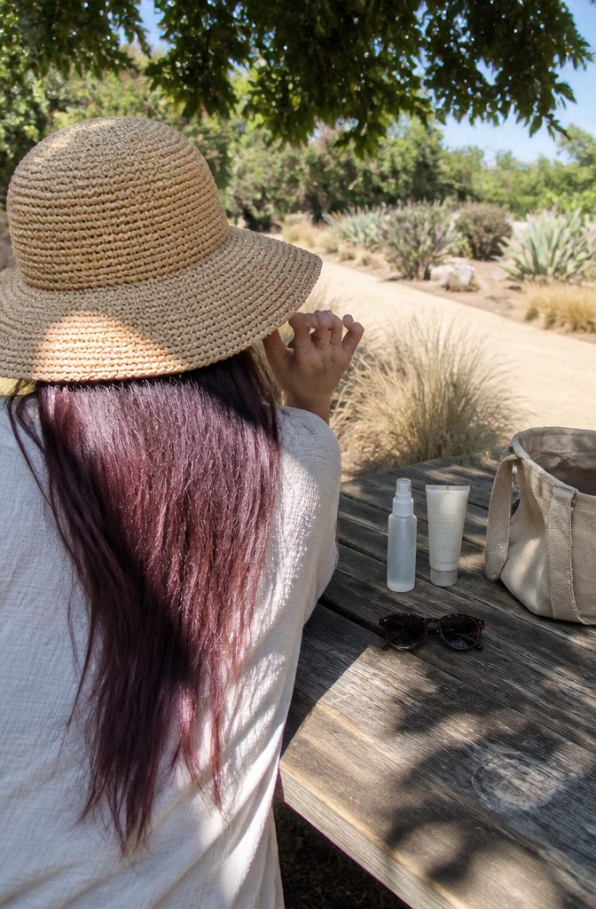 Colored long hair covered by a broad woven hat outdoors