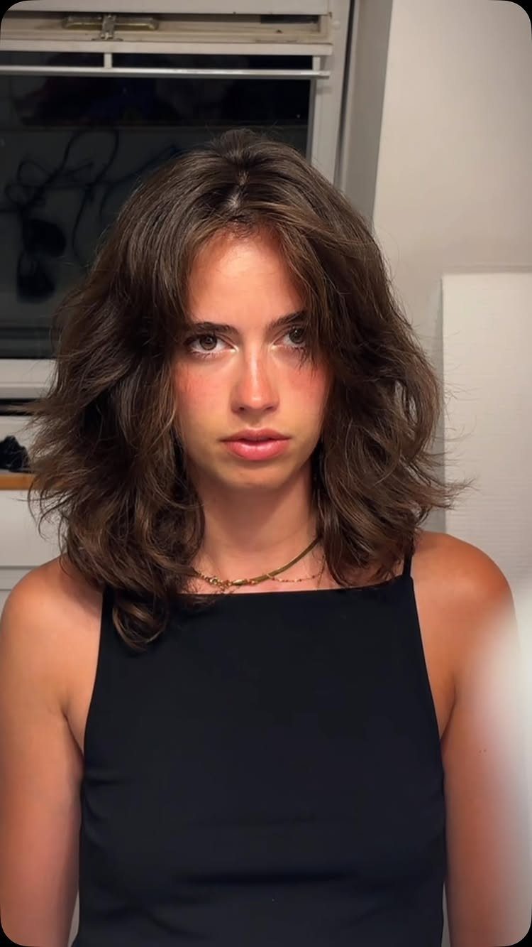 Young woman with tousled brown hair and soft, piecey French-girl fringe