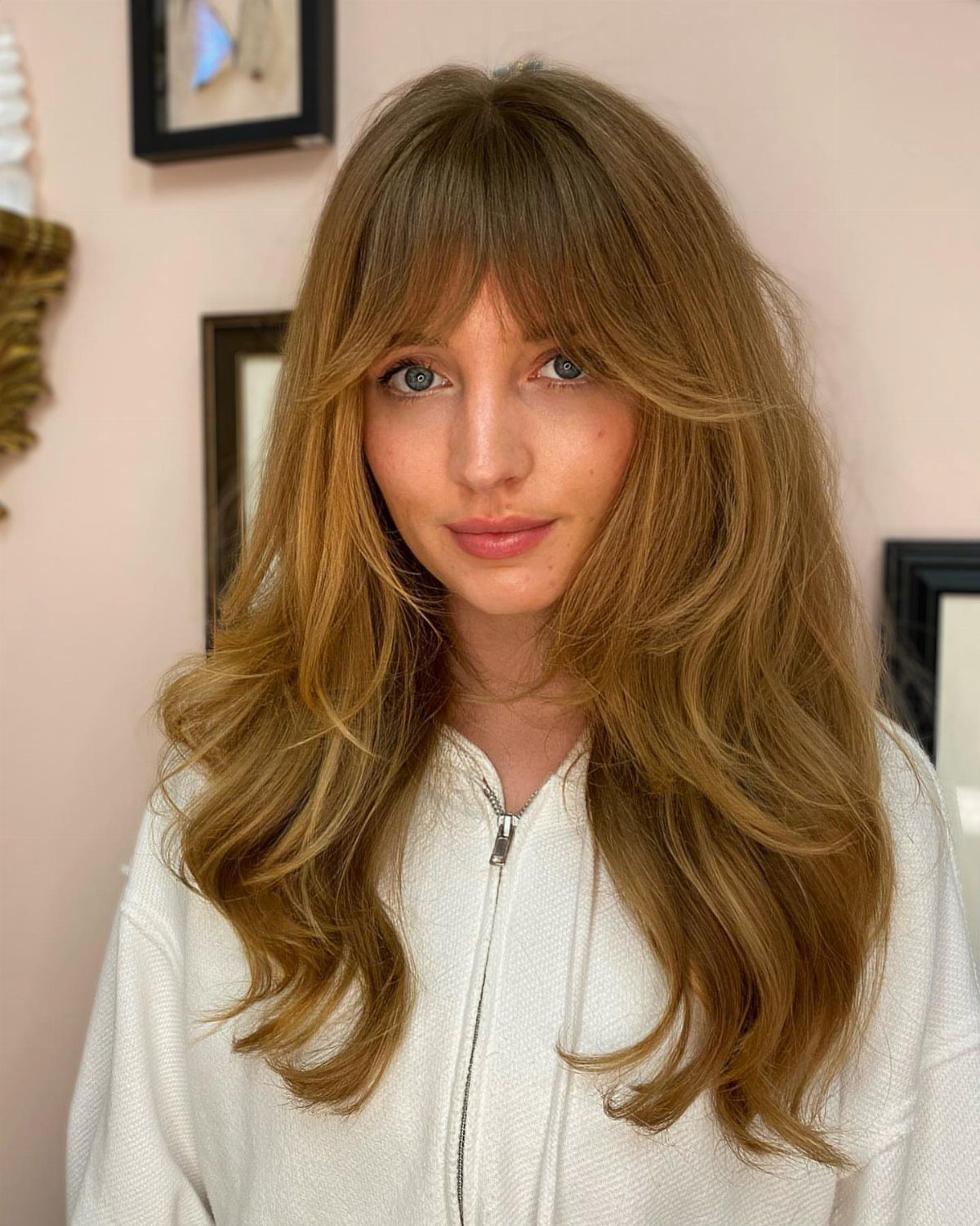 Woman with long brown hair and curved, swoopy bangs framing her face