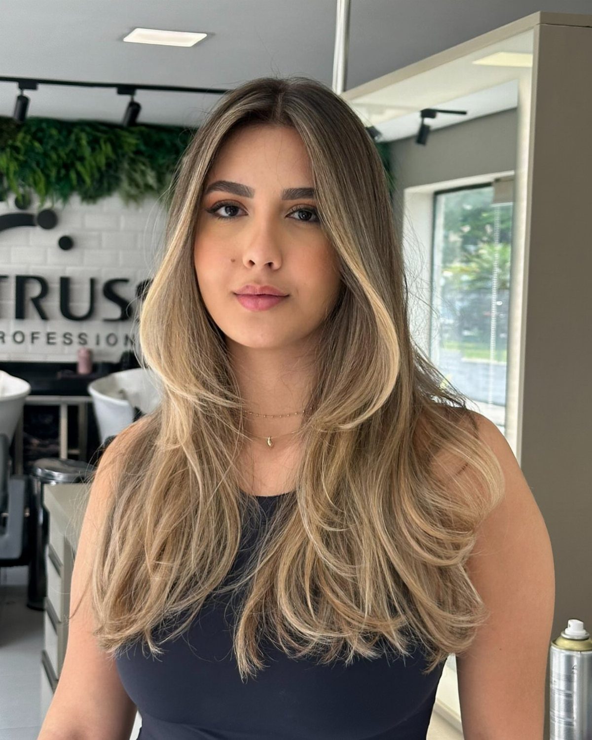Woman with long layered hair and blended blonde balayage highlights in a salon
