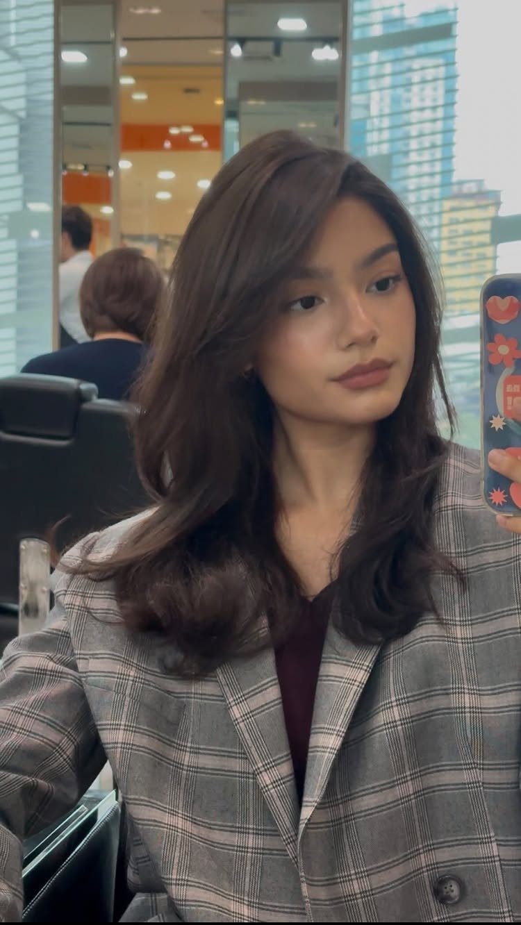 Woman showing long, voluminous layered dark hair in loose waves