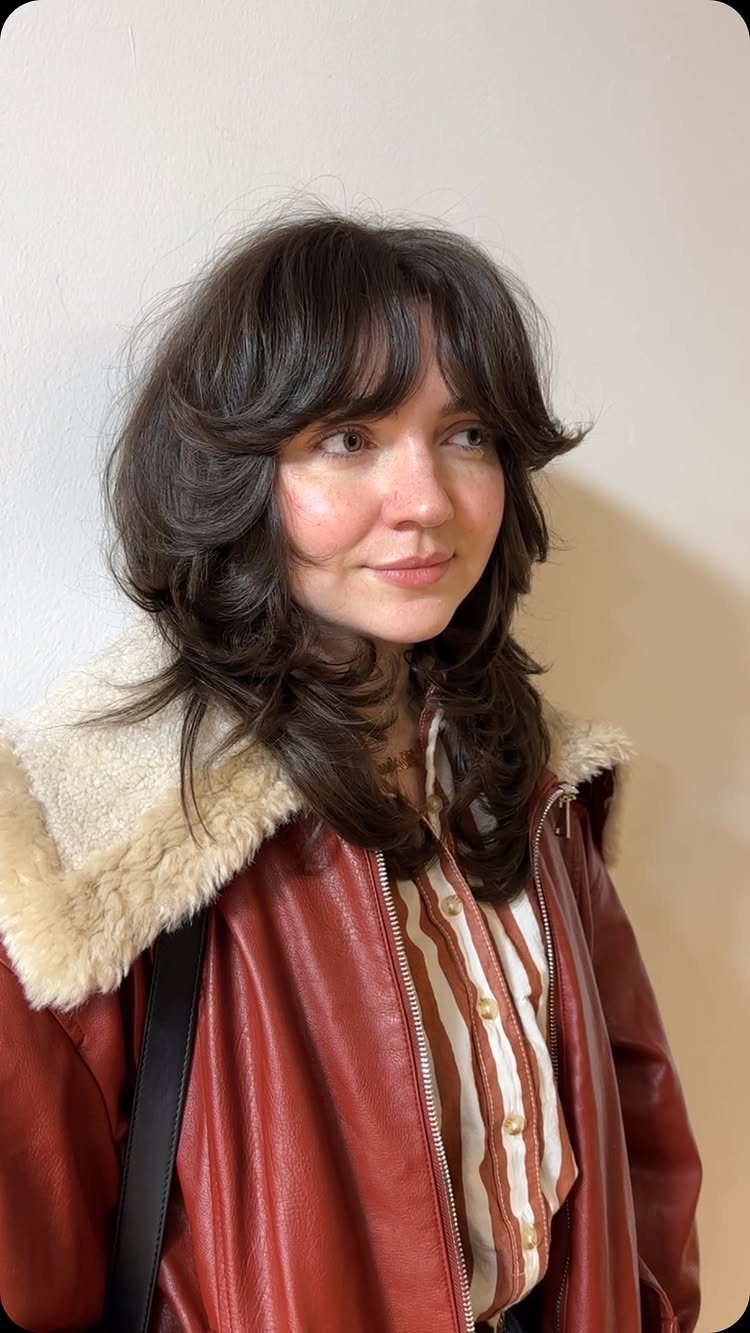 Woman showing long, choppy dark shag layers and curtain bangs