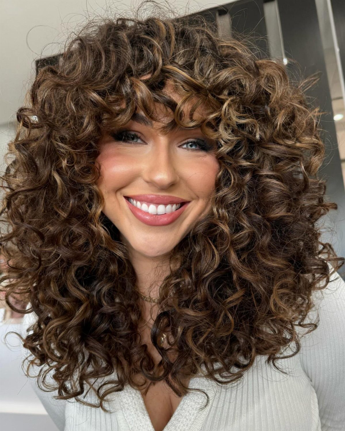 Woman showing long, voluminous brown curls with soft face-framing layers