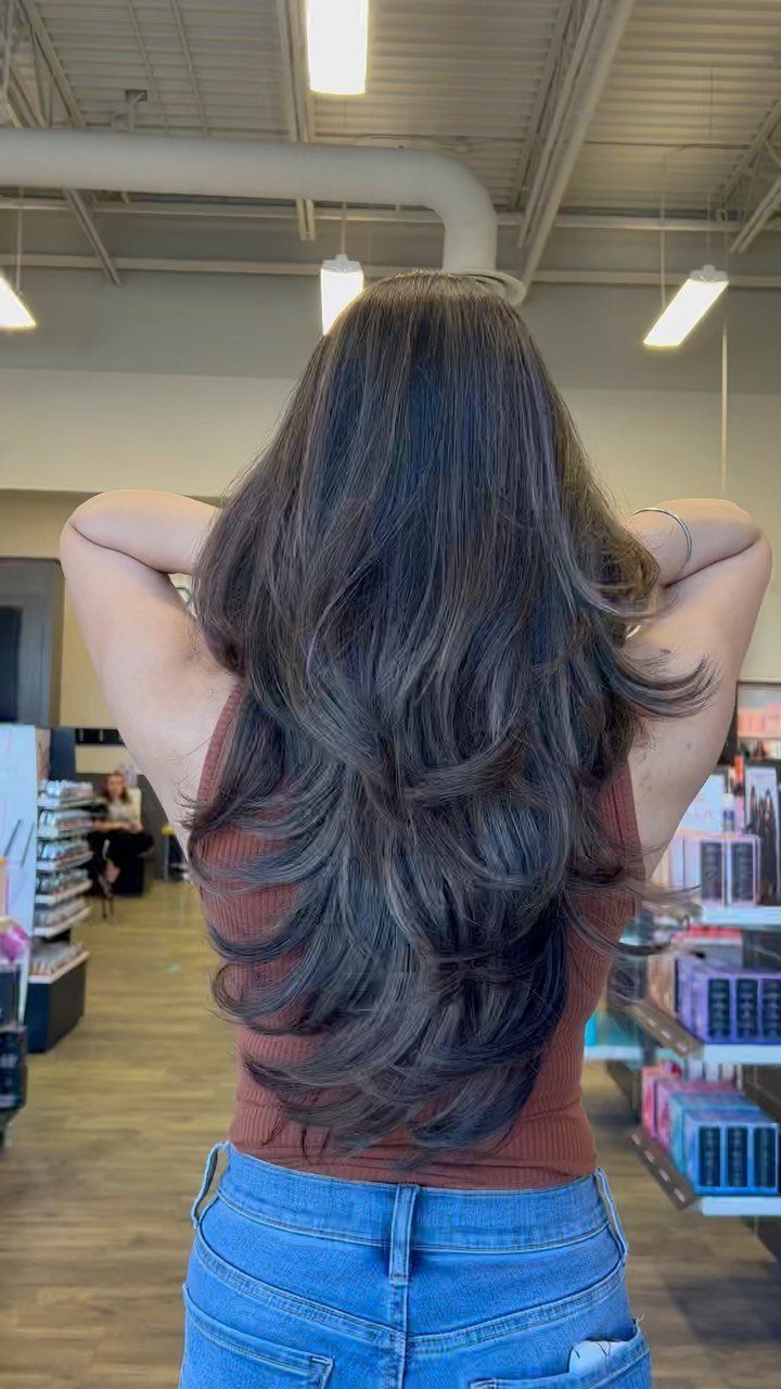 Long, thick dark hair with flowing layers shown from behind in a salon