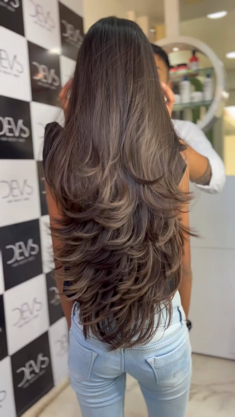 Long dark hair with blended cascading layers and curled ends in a salon