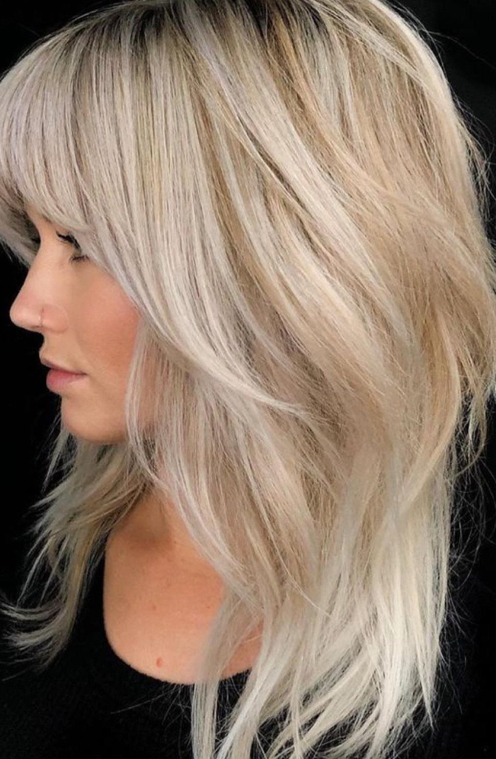 Long blonde hair with choppy, textured layers and sweeping bangs