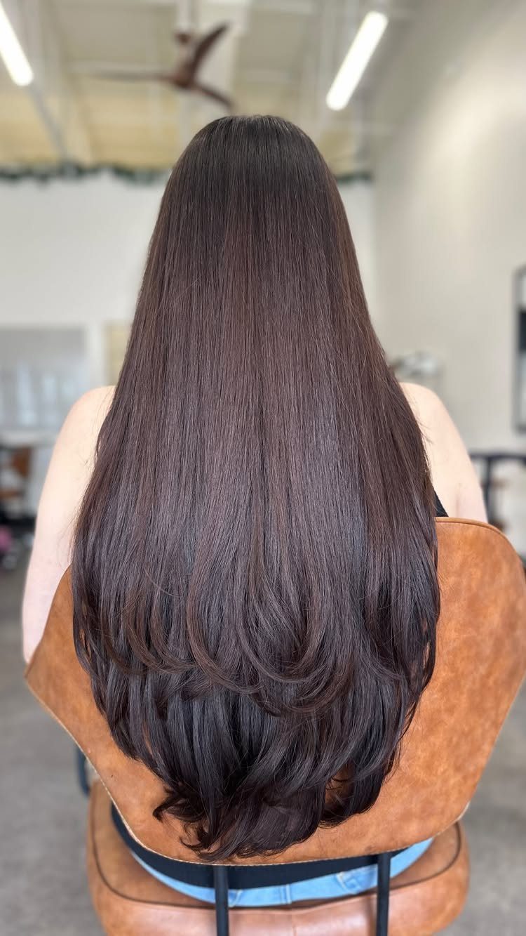 Long dark hair with smooth concave layers and curved ends in a salon chair