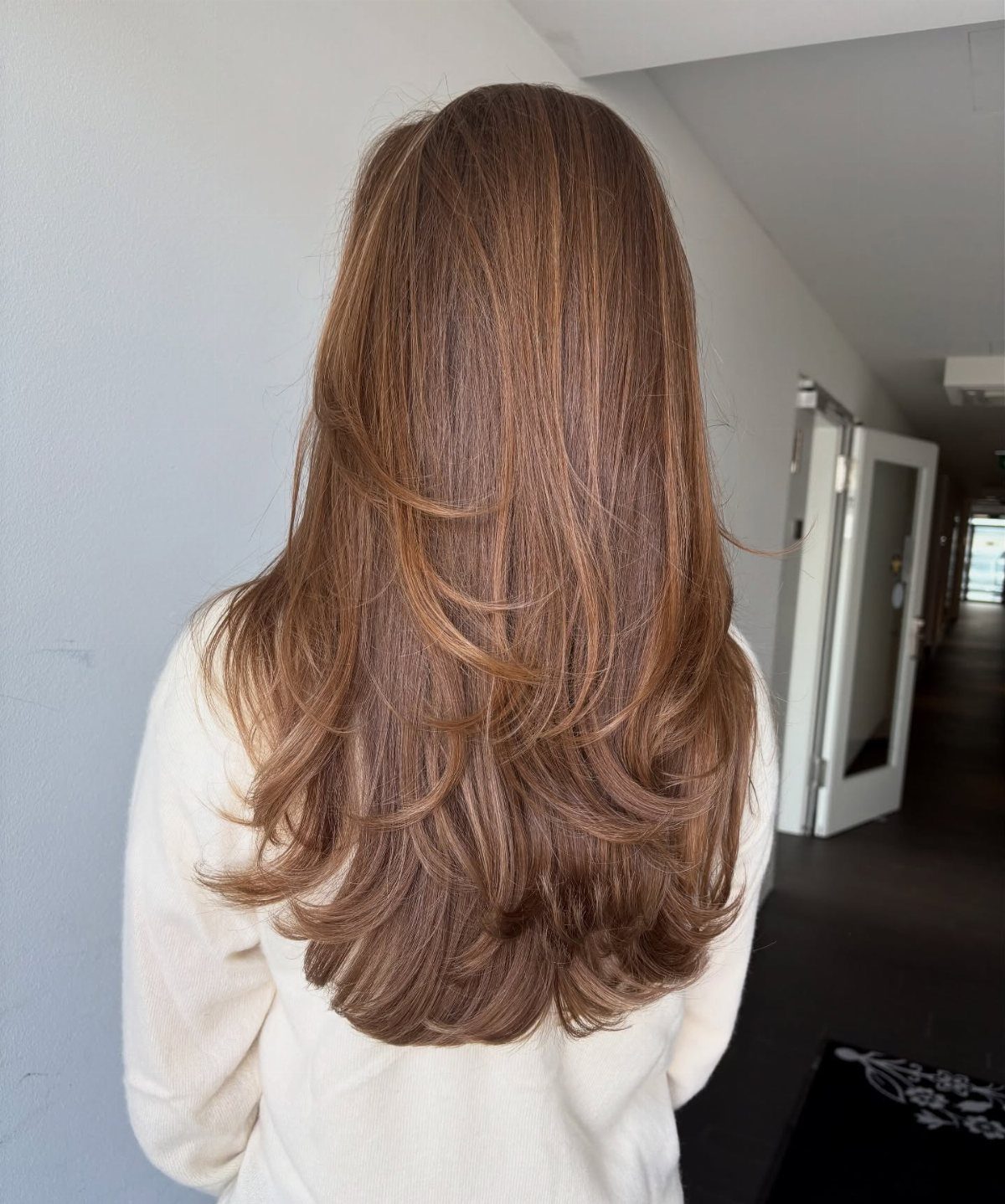 Long chestnut-brown hair styled in smooth, rounded layers with curled ends