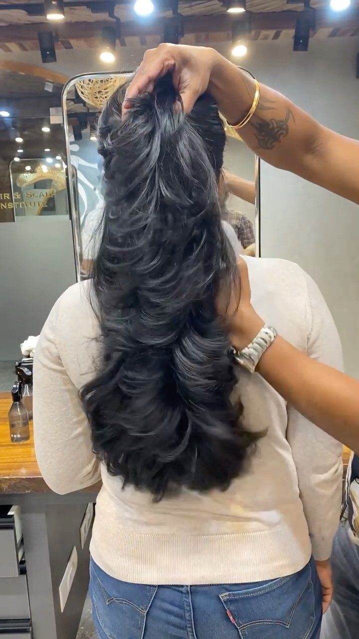 Long dark feathered layers cascade down a salon client's back