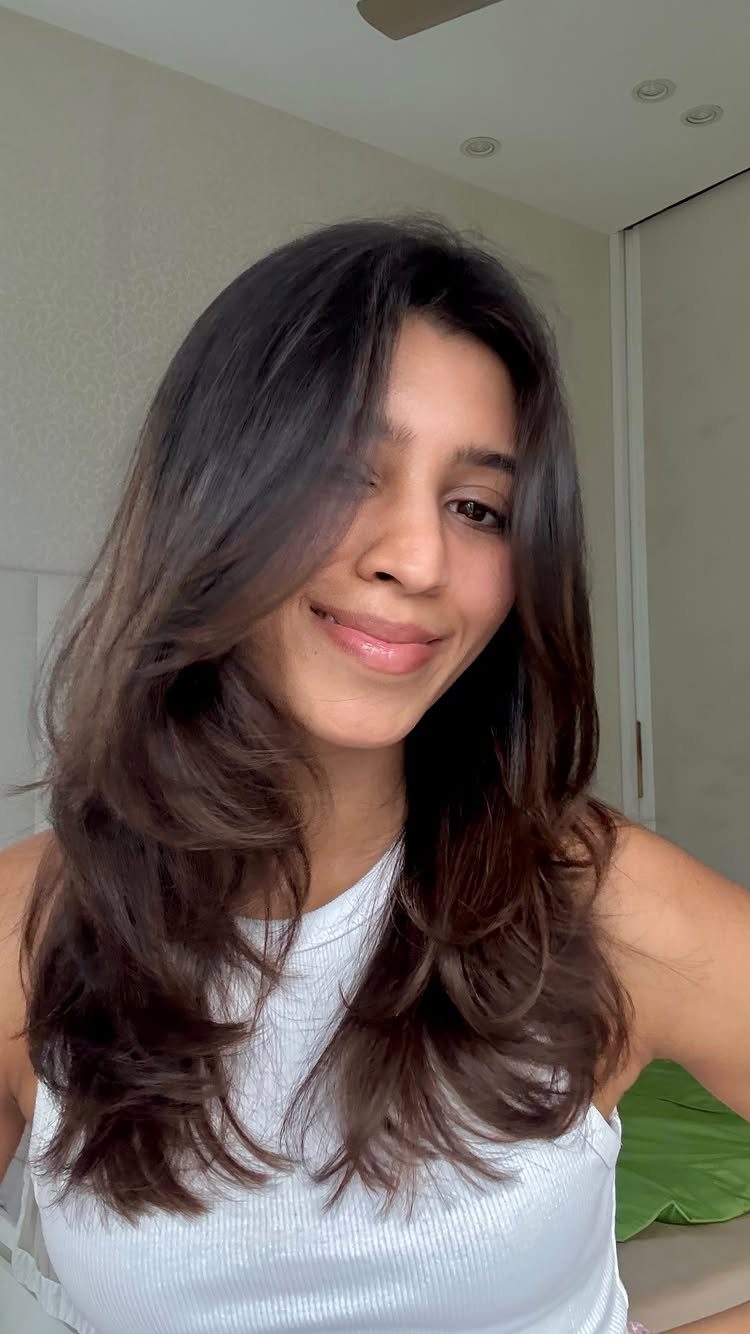 Woman with long dark brown hair styled in soft, full layers