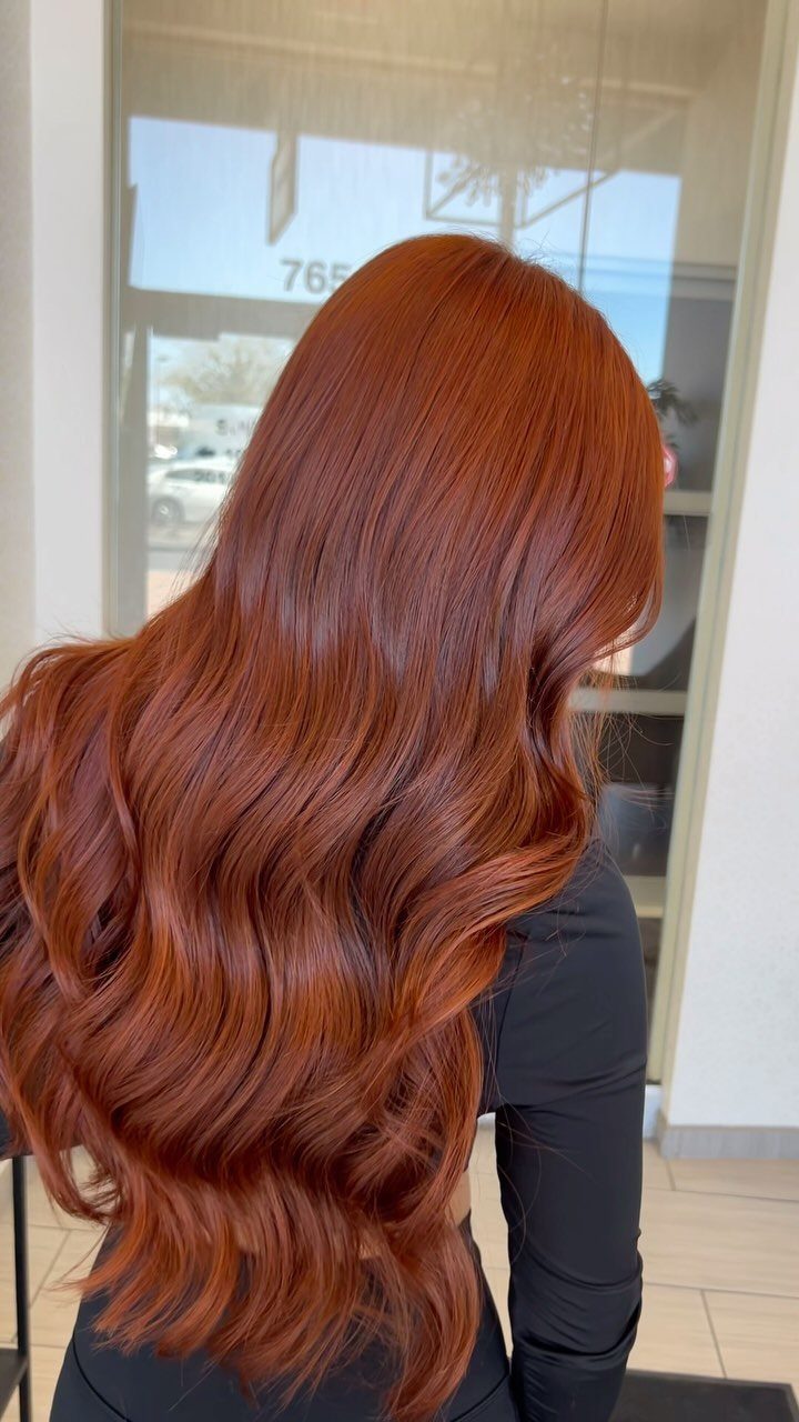 Long copper hair falls in glossy waves with soft, layered ends