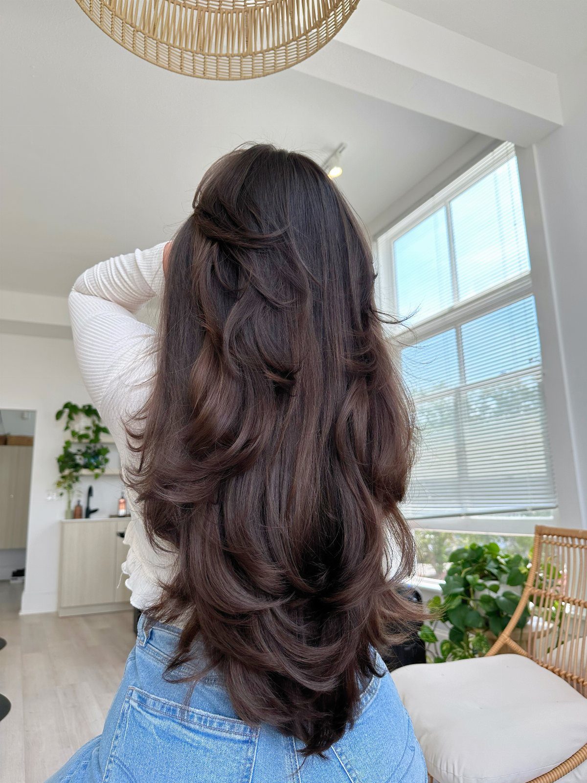 Long dark brown hair falls in loose, voluminous layered waves down the back.