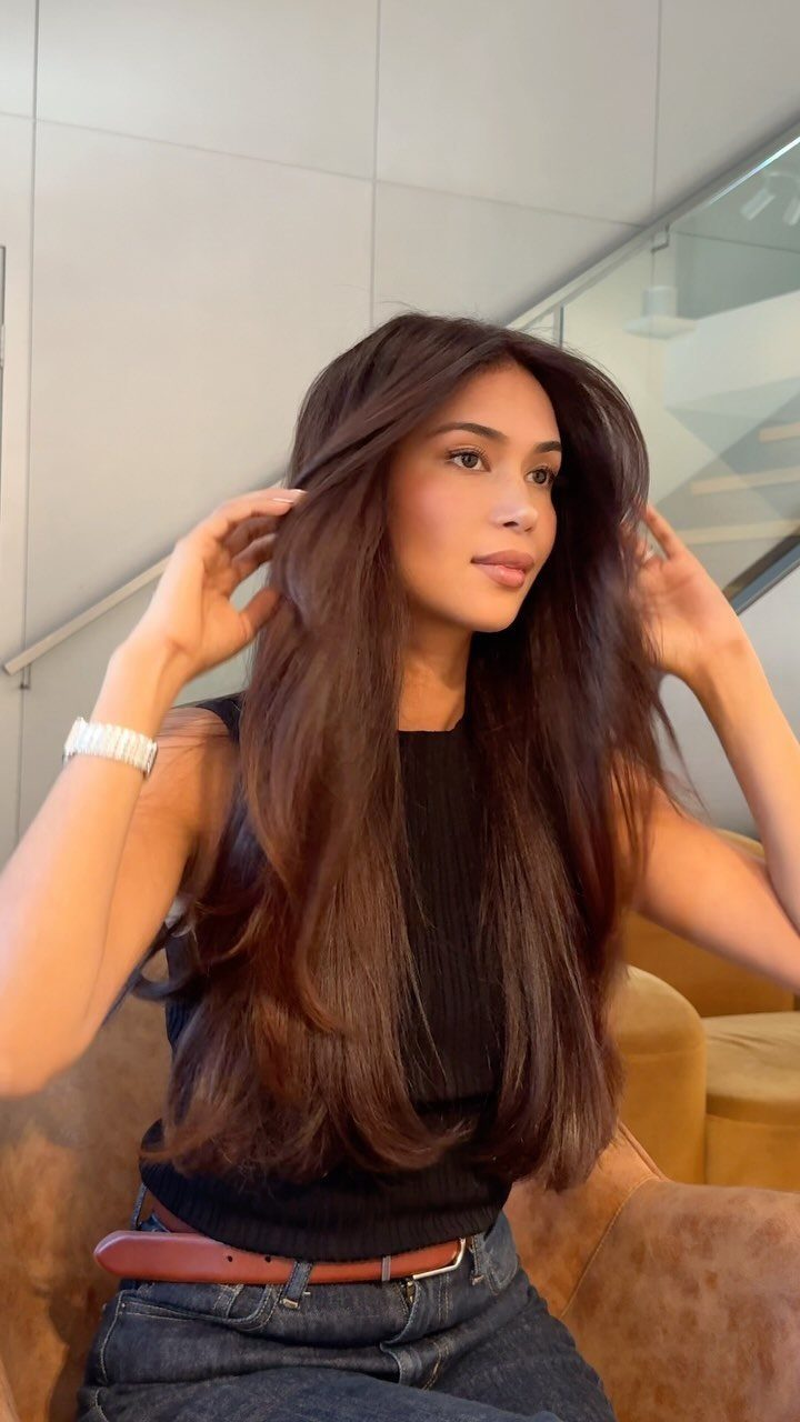 Woman displaying long, smooth dark brown hair with a mostly blunt, subtly layered cut