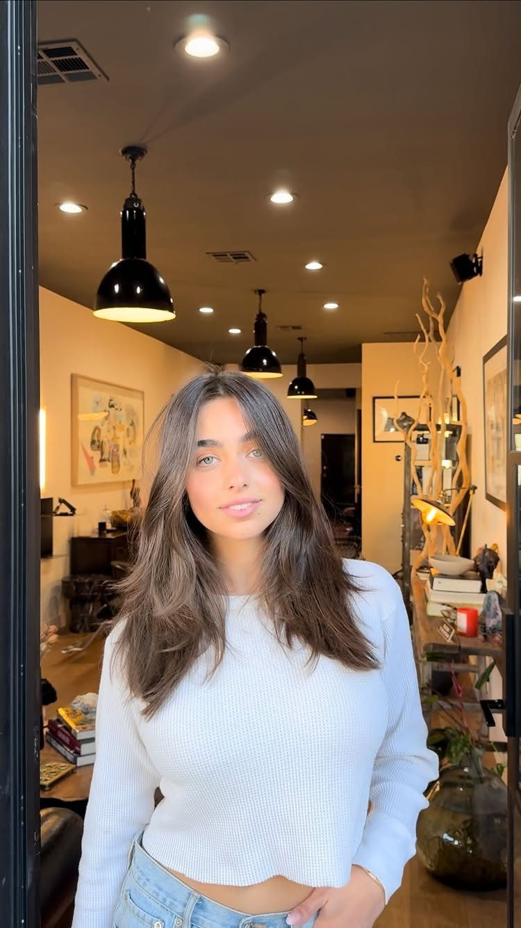 Woman with long dark hair and swoopy layers standing inside a salon