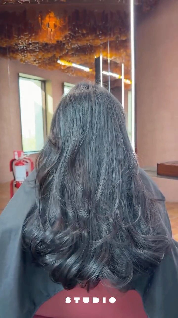 Long dark wavy hair with layered curls and a rounded U-shaped hemline