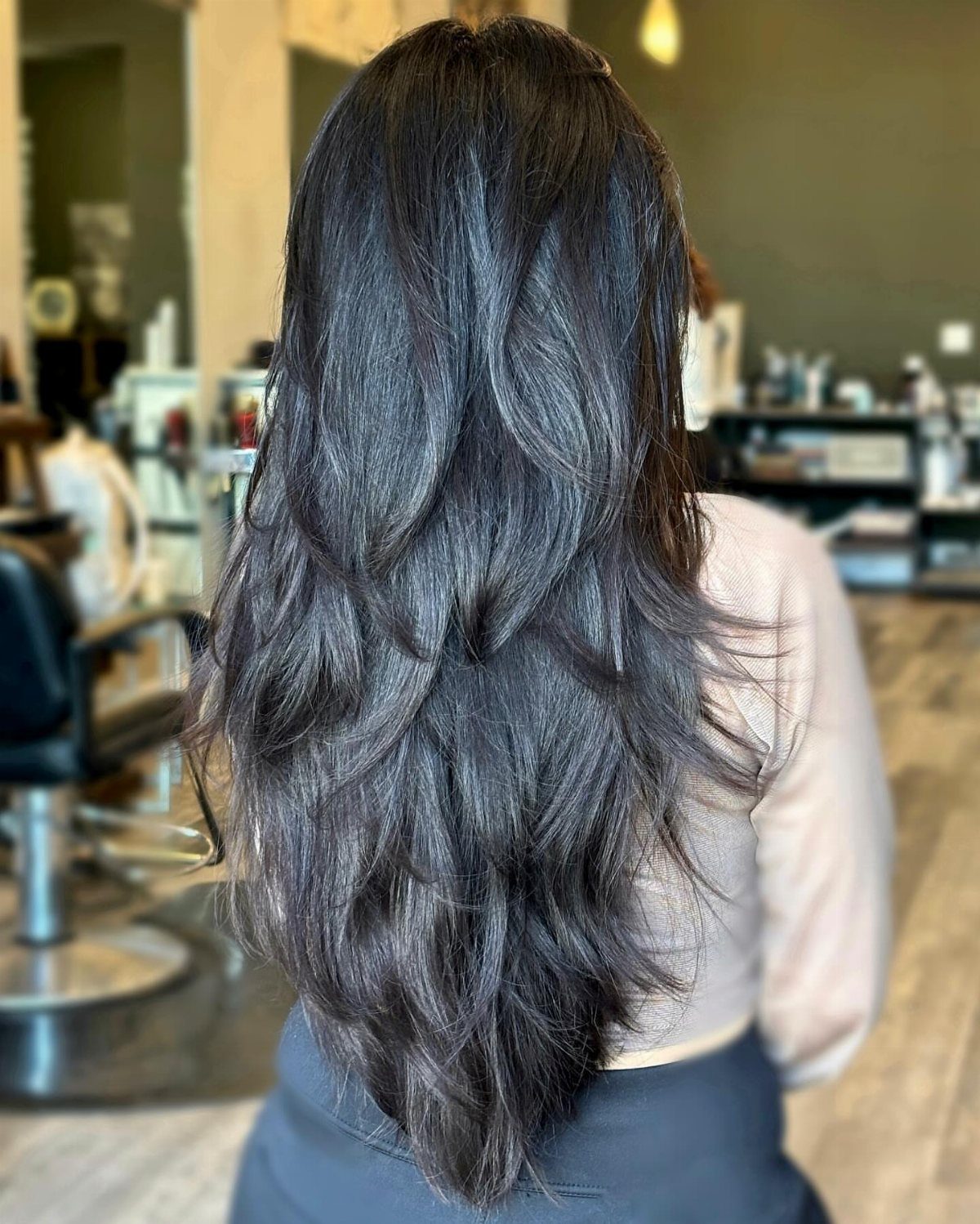 Long dark hair with swooping layers tapering into a sharp V-shaped hemline