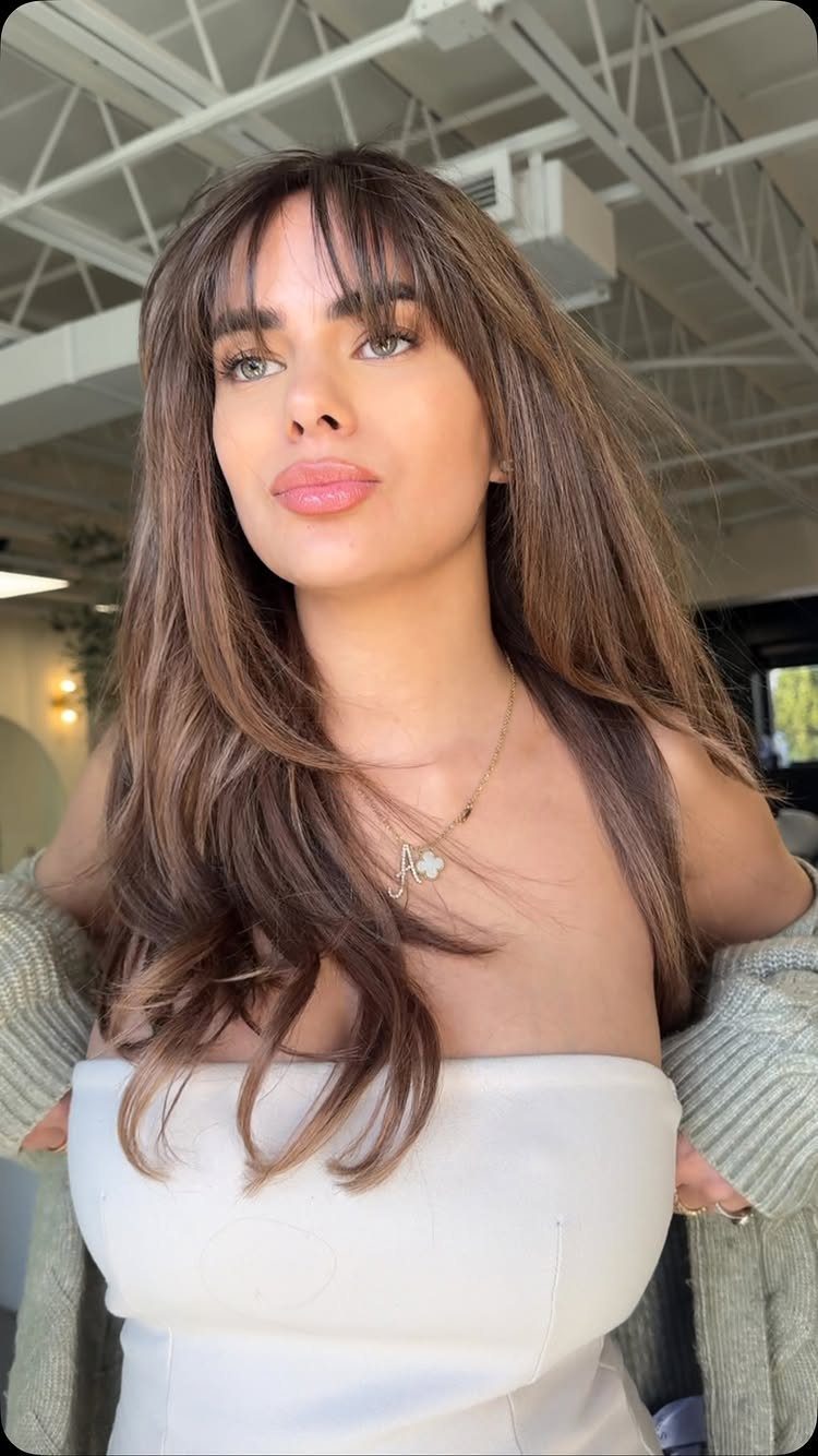 Woman with long blended brown layers and relaxed wispy fringe
