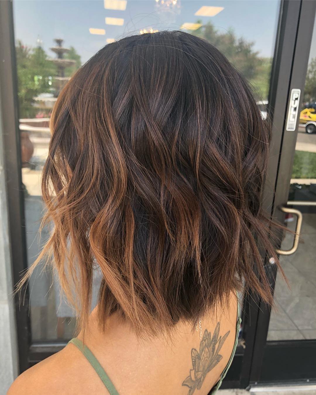 Choppy shoulder-length brunette lob with wavy layers and lighter ends