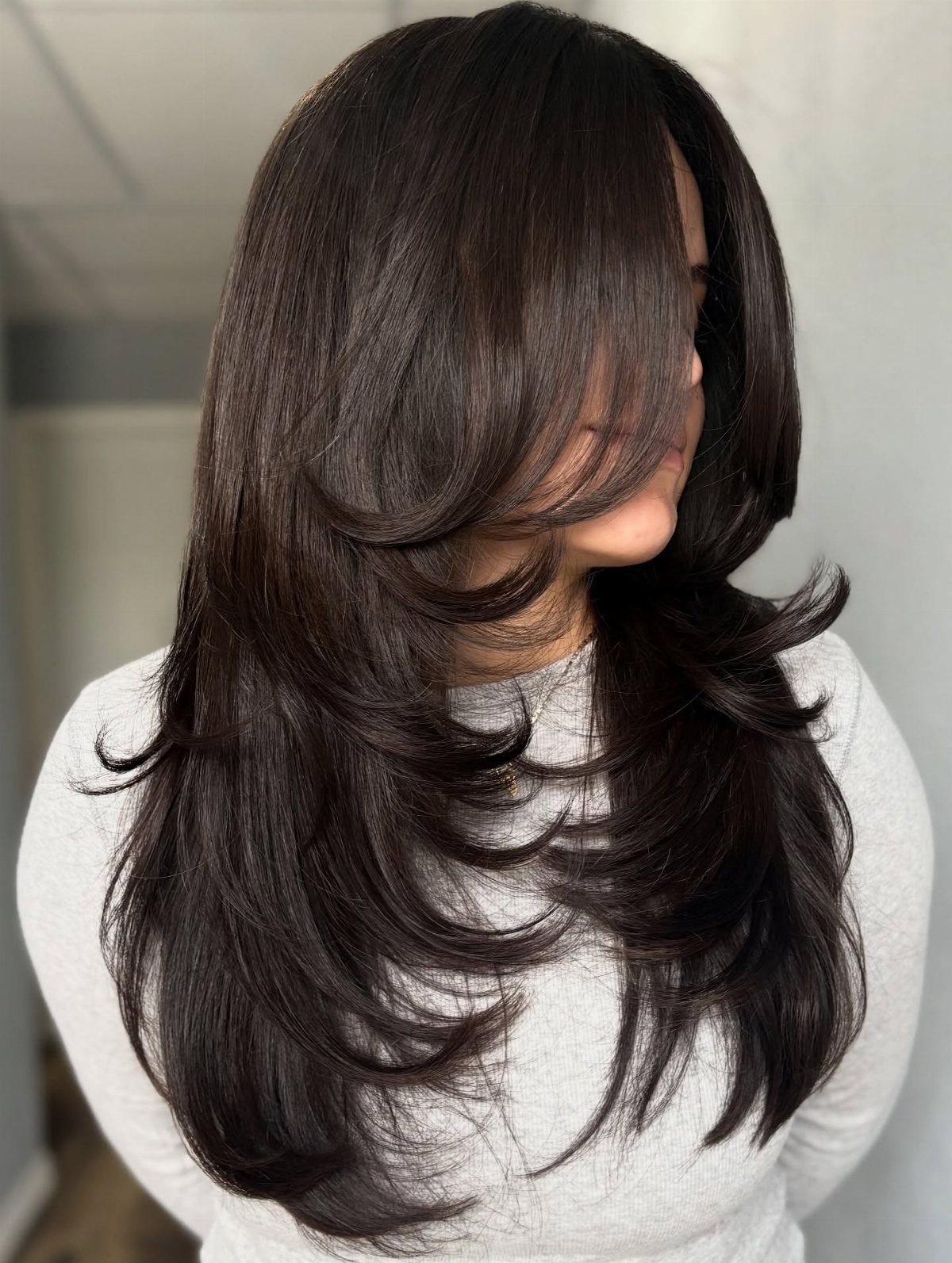 Long dark hair with sweeping face-framing layers and feathered ends