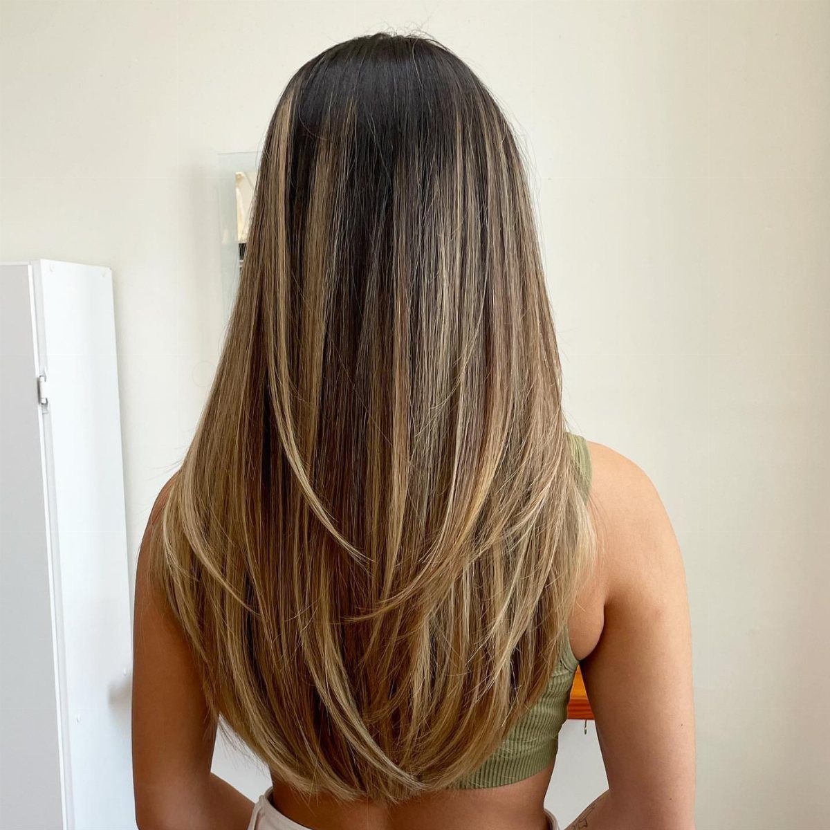 Layered brown and blonde medium-length hair falls in a rounded shape