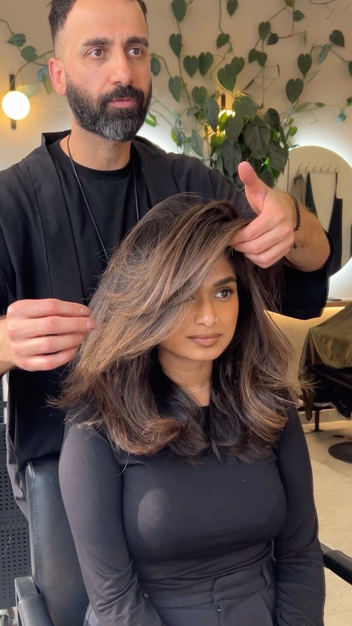 Woman displaying mid-length layered brunette hair with highlights at a salon
