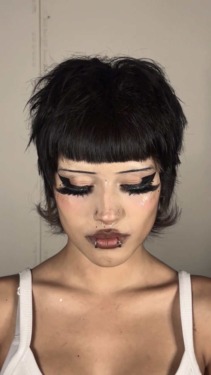 Person showing a tousled dark pixie cut with blunt bangs and longer sides