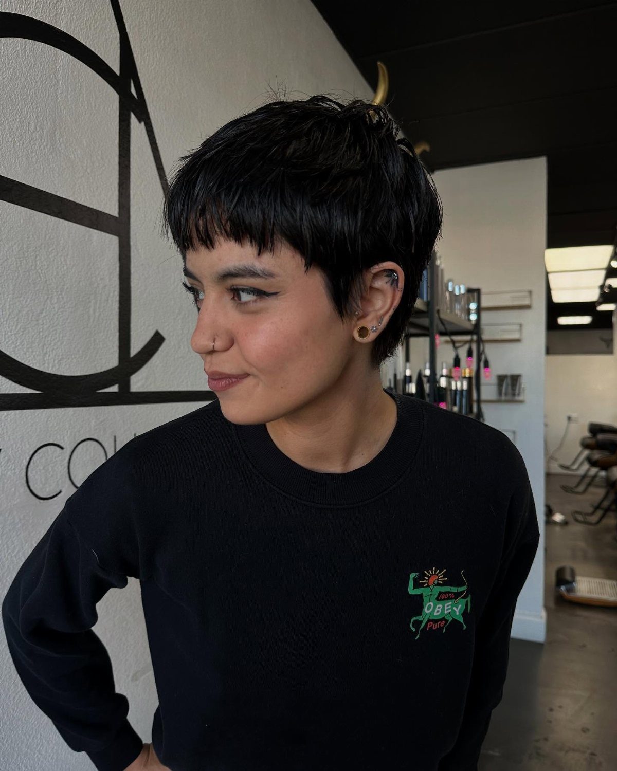 Person with dark textured long pixie hair and a short fringe