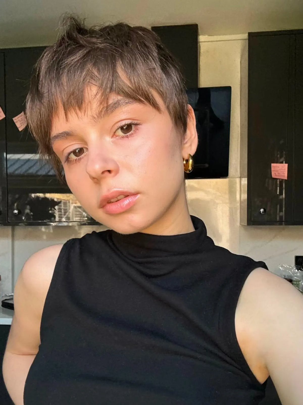 Person with straight brown hair in a layered pixie cut with wispy bangs