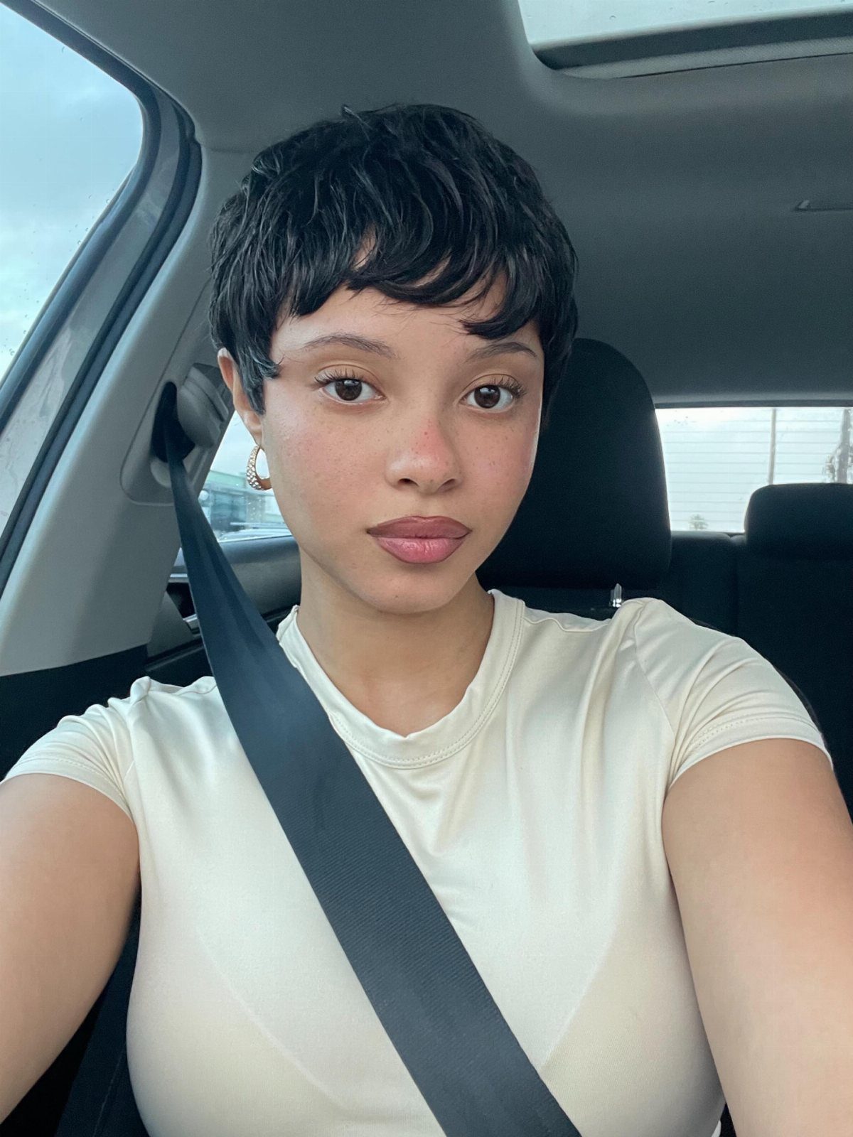 Woman with a short dark pixie cut and side-swept wavy fringe