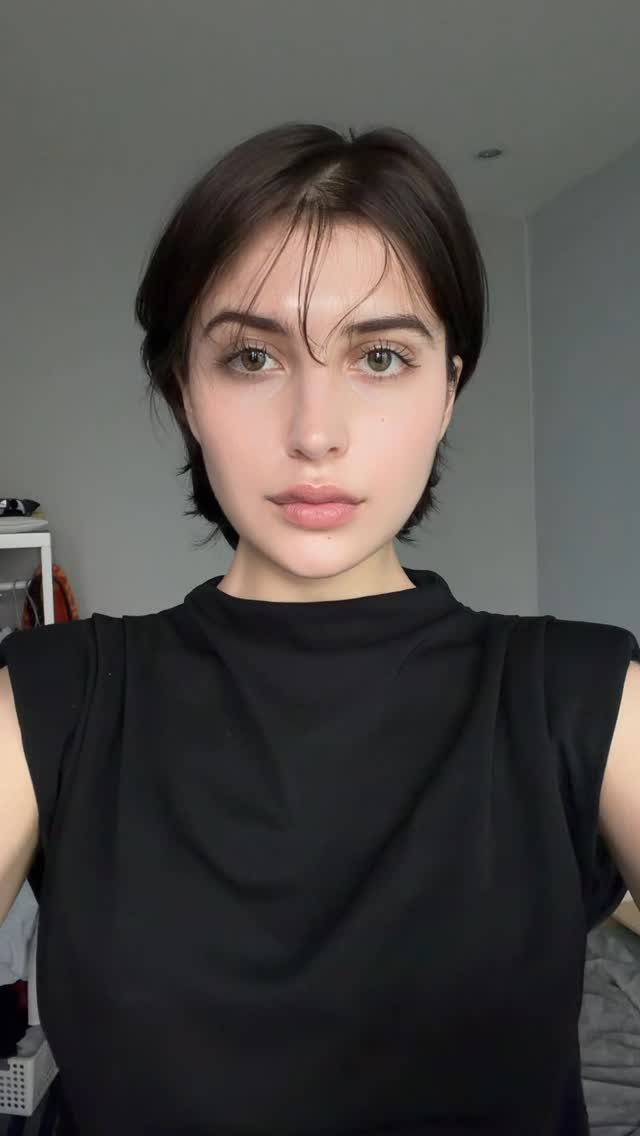 Woman with a dark long pixie cut and wispy bangs facing the camera