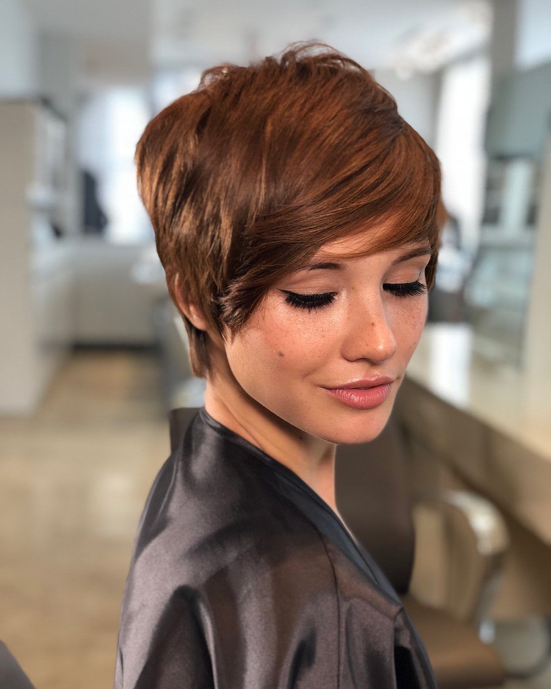 Woman with a voluminous auburn pixie styled in a deep side sweep