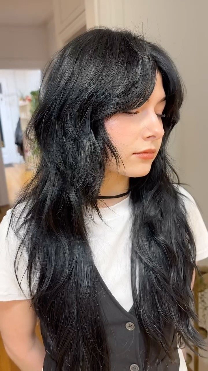 Long black shag haircut with glossy layers and sweeping bangs