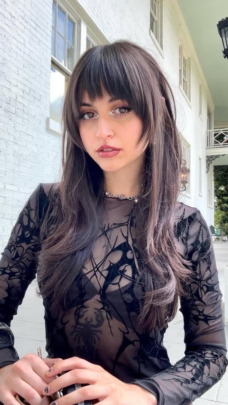 Woman with long dark layered hair, soft fringe, and wispy ends
