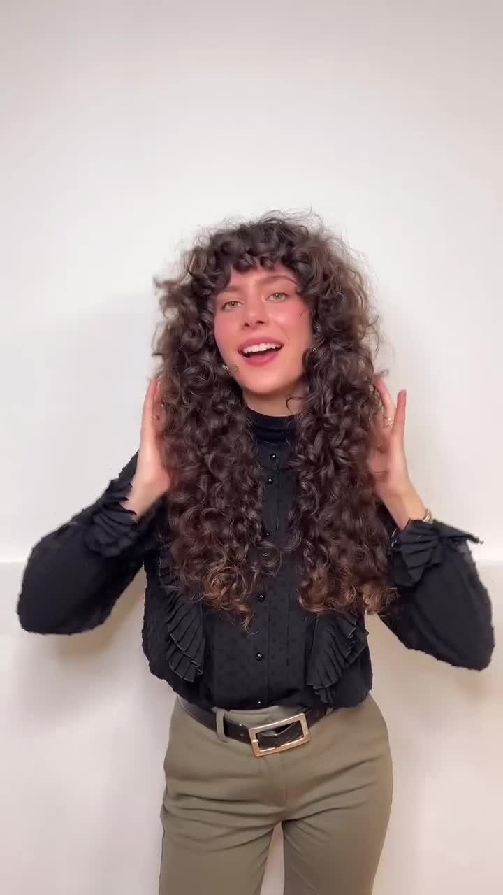 Person showing long dark curls with shaggy layers and bangs