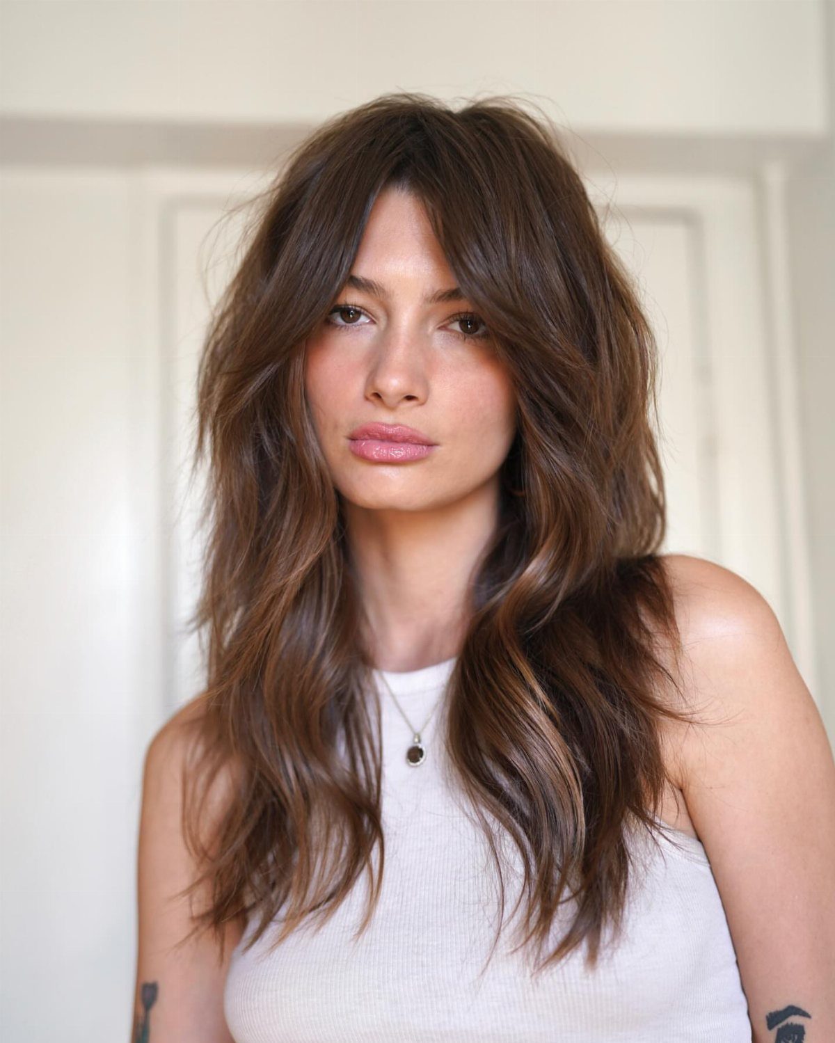 Woman with long brown shag layers and center-parted curtain bangs