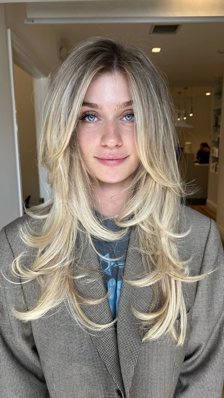 Woman with long blonde hair styled in cascading feathered shag layers