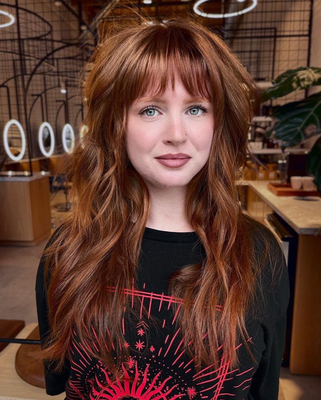 Woman with long ginger shag haircut, wispy bangs and soft face-framing layers