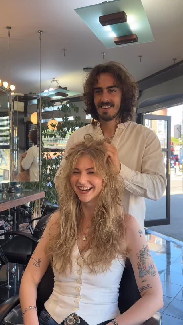 Woman with long, layered blonde shag haircut sitting in a salon chair