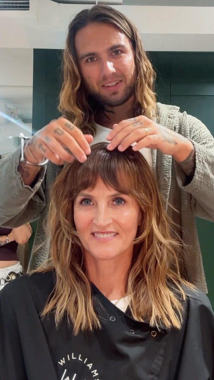 Woman with long, soft wavy shag haircut and bangs in a salon