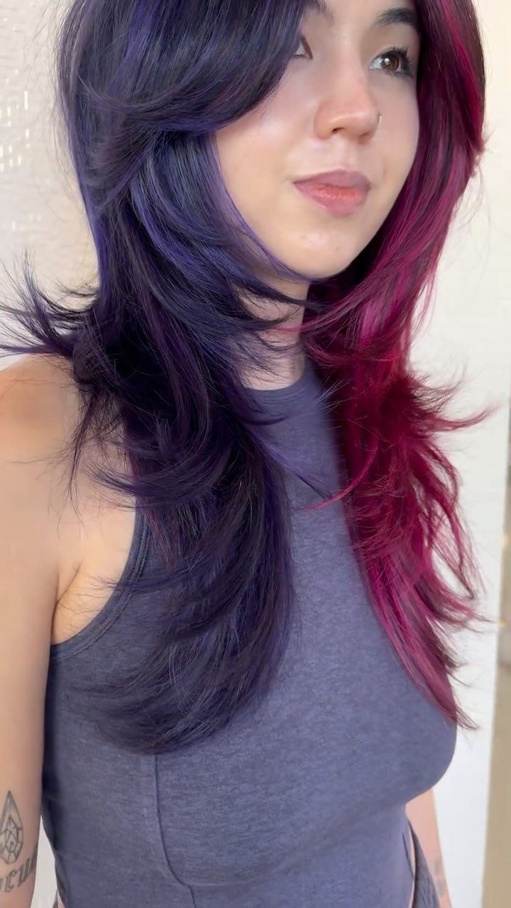 Person with long layered shag hair split between dark purple and magenta