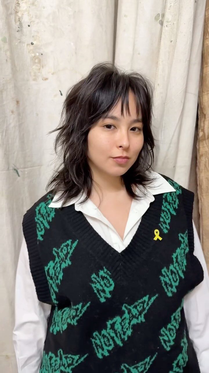 Woman with short choppy bangs and shoulder-length wavy layered dark hair