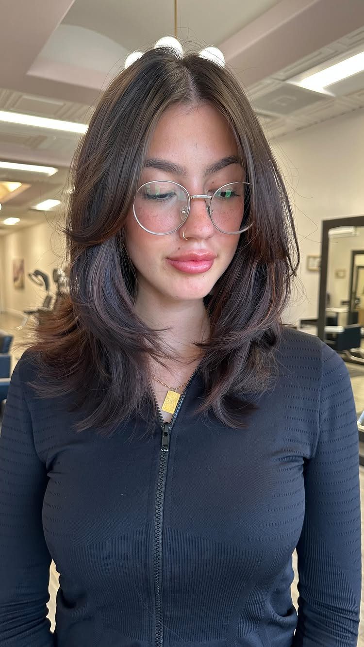 Woman with dark layered hair and curtain bangs framing her face