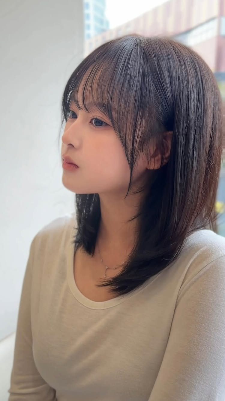 Woman with straight shoulder-length dark hair and wispy forehead-framing bangs
