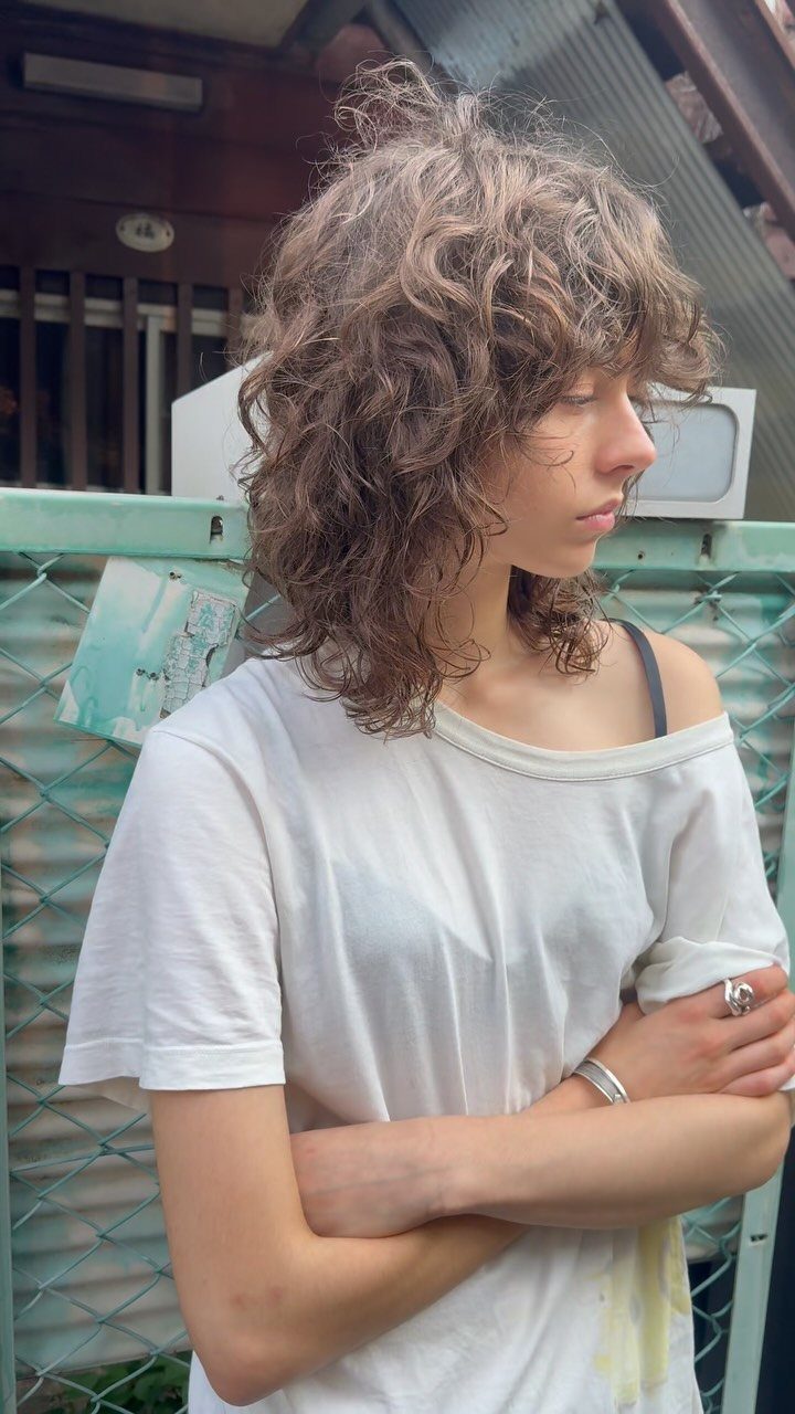 Shoulder-length curly shag with abundant tousled brown layers and side-swept fringe