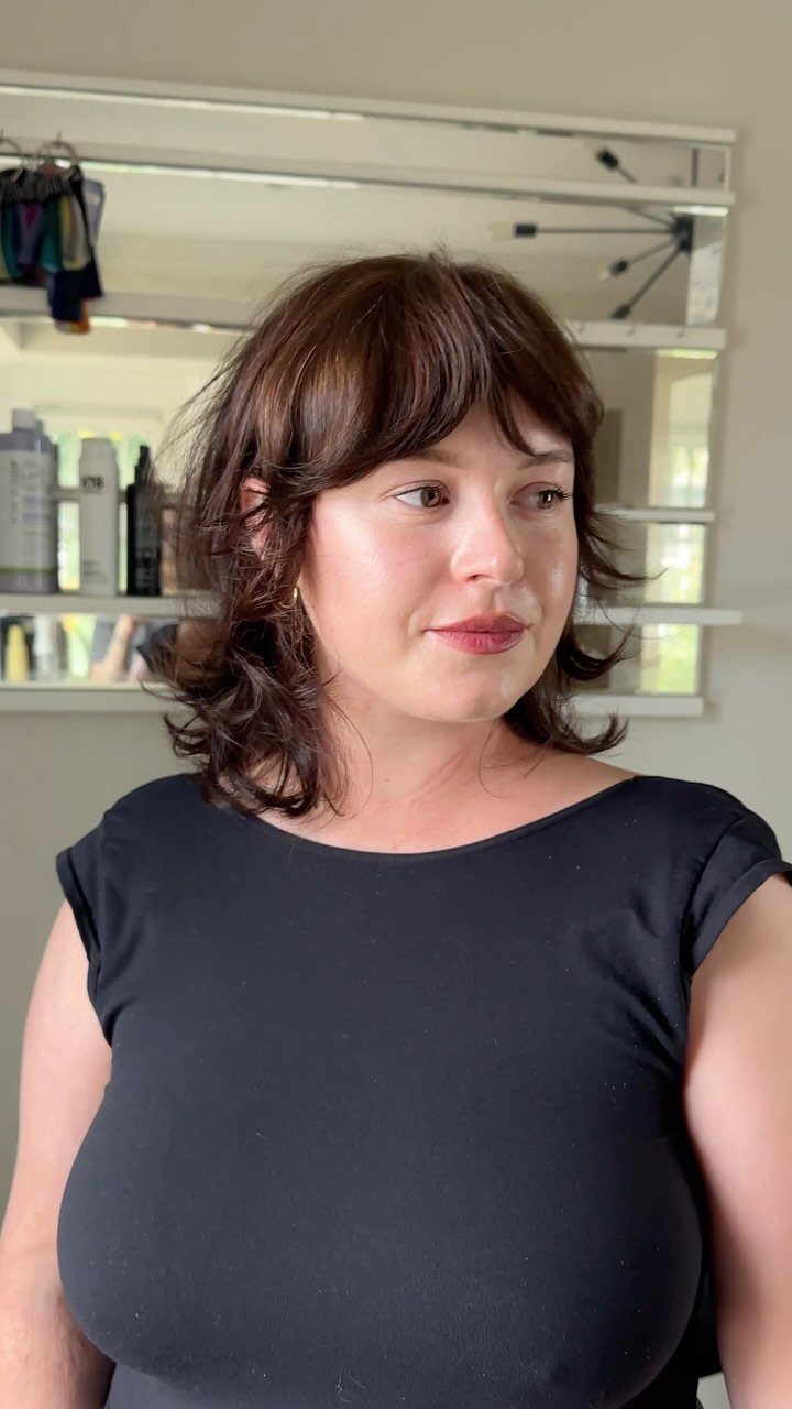 Woman showing a shaggy midi haircut with wispy bangs and feathered ends
