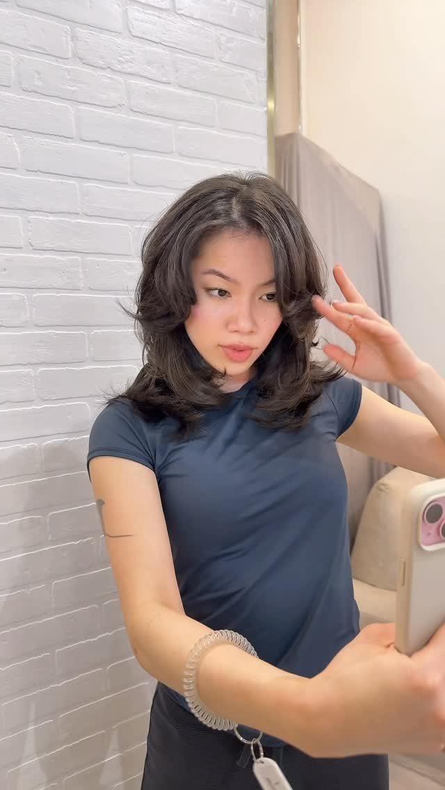 Person showing shoulder-length layered lob with angled sections in mirror selfie